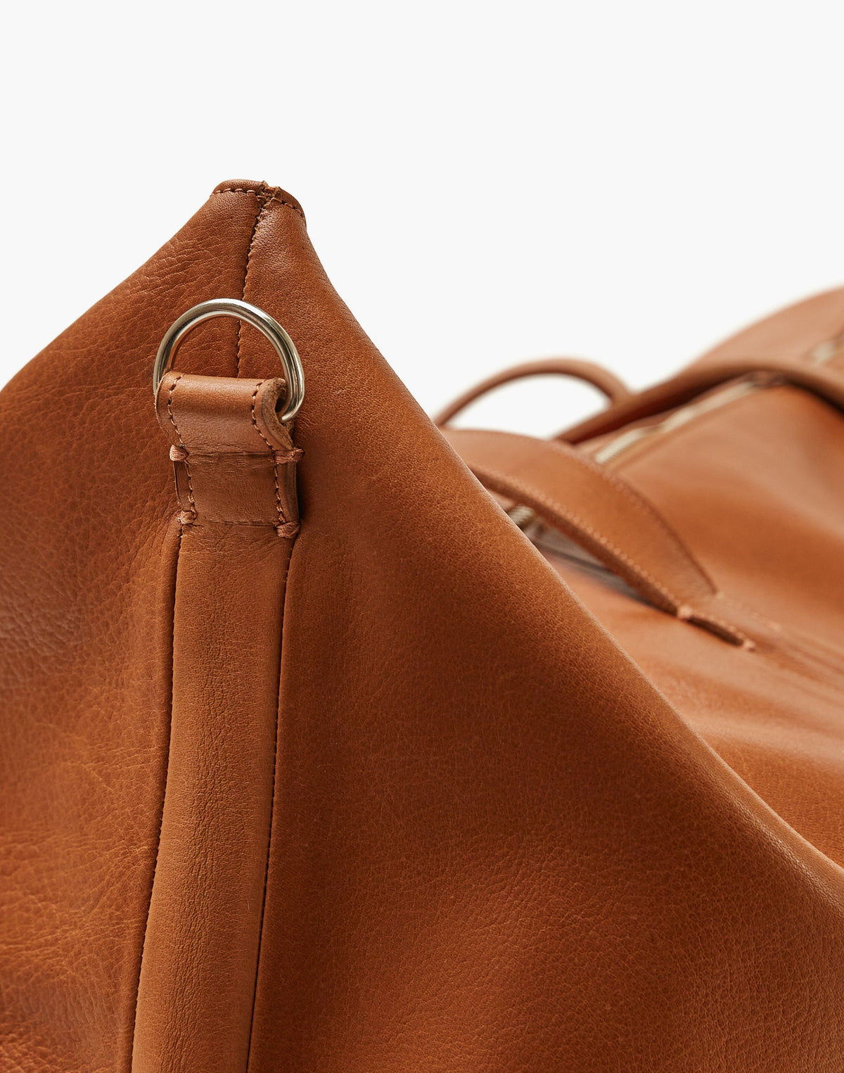 Close-up of the Malbec weekender in Tobacco, showing the metal strap ring, stitched leather attachment, and natural surface texture.