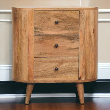 Oak-ish solid wood mini cabinet styled in bedroom setting with three drawers and Nordic splayed legs on hardwood floor