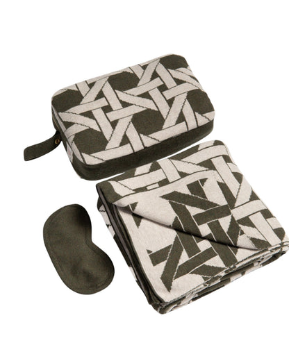 Olive green organic cotton travel blanket set with geometric pattern including compact pouch folded blanket and eye mask angled flat lay