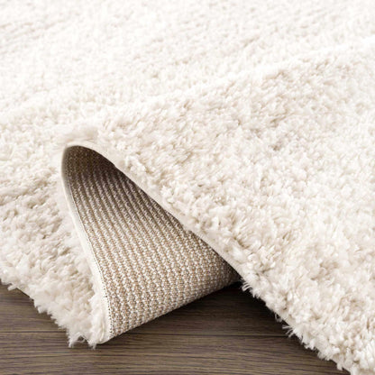 Plush Beige Shag Rug Folded Corner on Hardwood Floor Showing Woven Backing and Deep Pile | Fluent Trends
