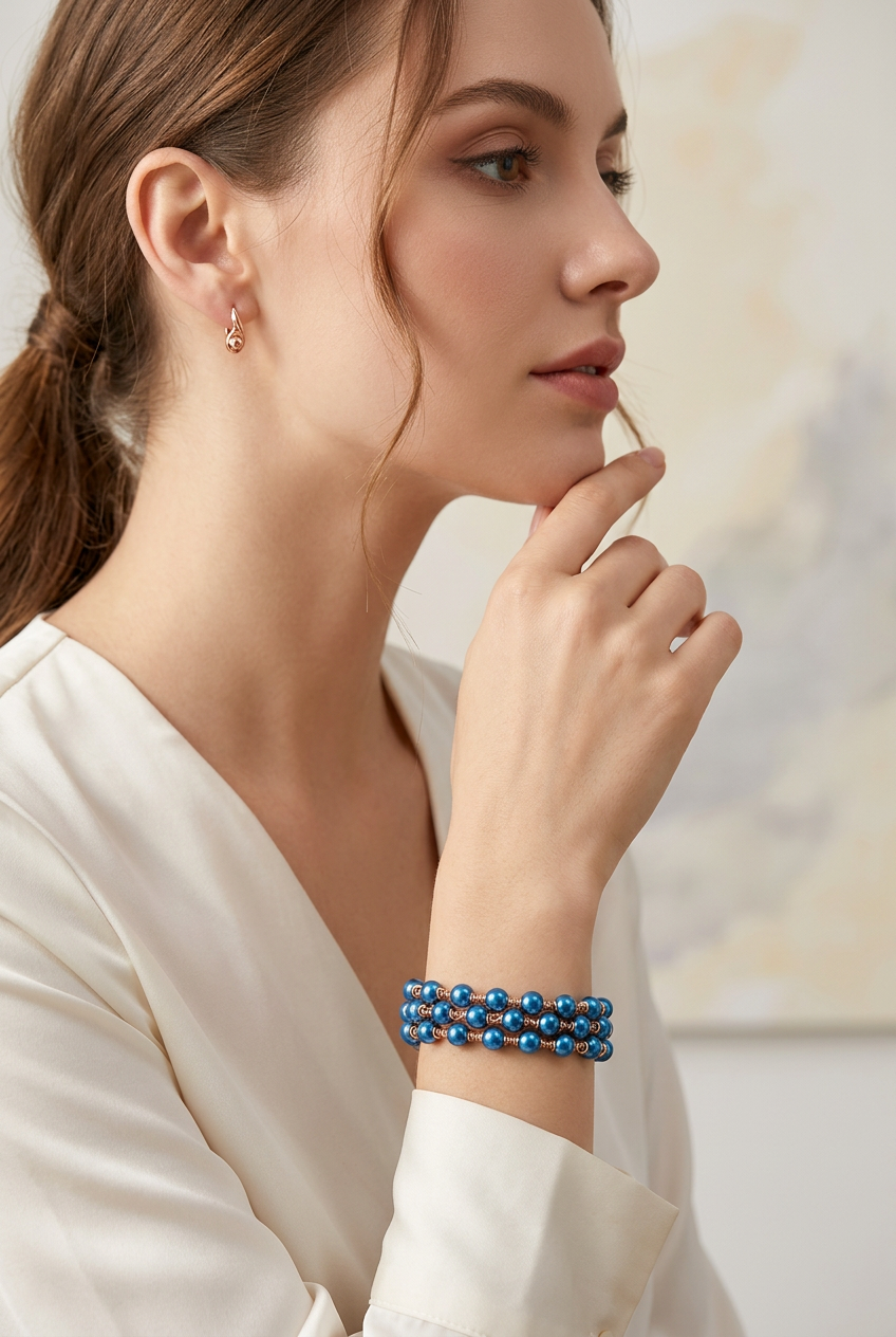 Model wearing a Celeste blue hematite artisan bracelet with three beaded strands and rose-gold-tone wirework, paired with a white blouse.