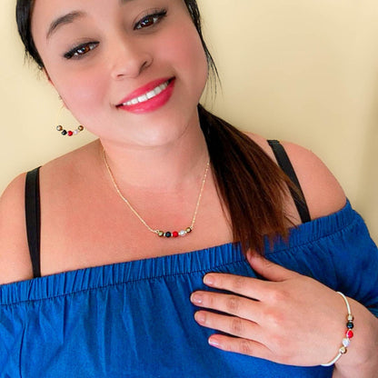 Model wearing His-Story Majorca pearl hoop earrings with a coordinating necklace and bangle bracelet, styled with a blue off-the-shoulder top.