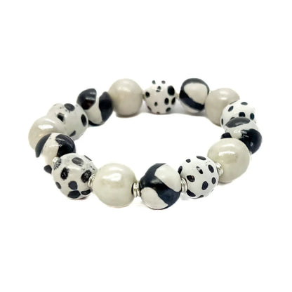 Sefone artisan bracelet with cream clay beads, spotted and abstract black-and-white patterns, and small silver-tone spacers on a white background.