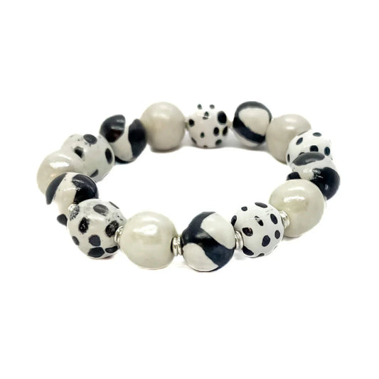 Sefone artisan bracelet with cream clay beads, spotted and abstract black-and-white patterns, and small silver-tone spacers on a white background.