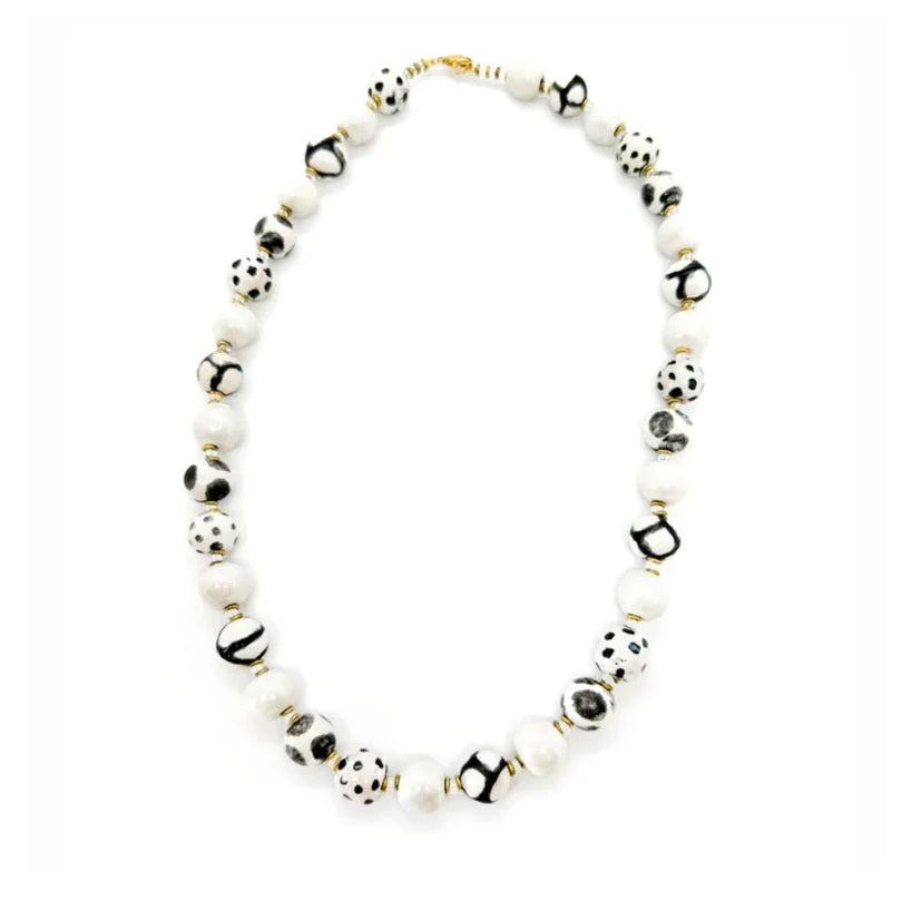 Sefone artisan necklace with cream clay beads, spotted and abstract black-and-white patterns, and small gold-tone accents on a white background.