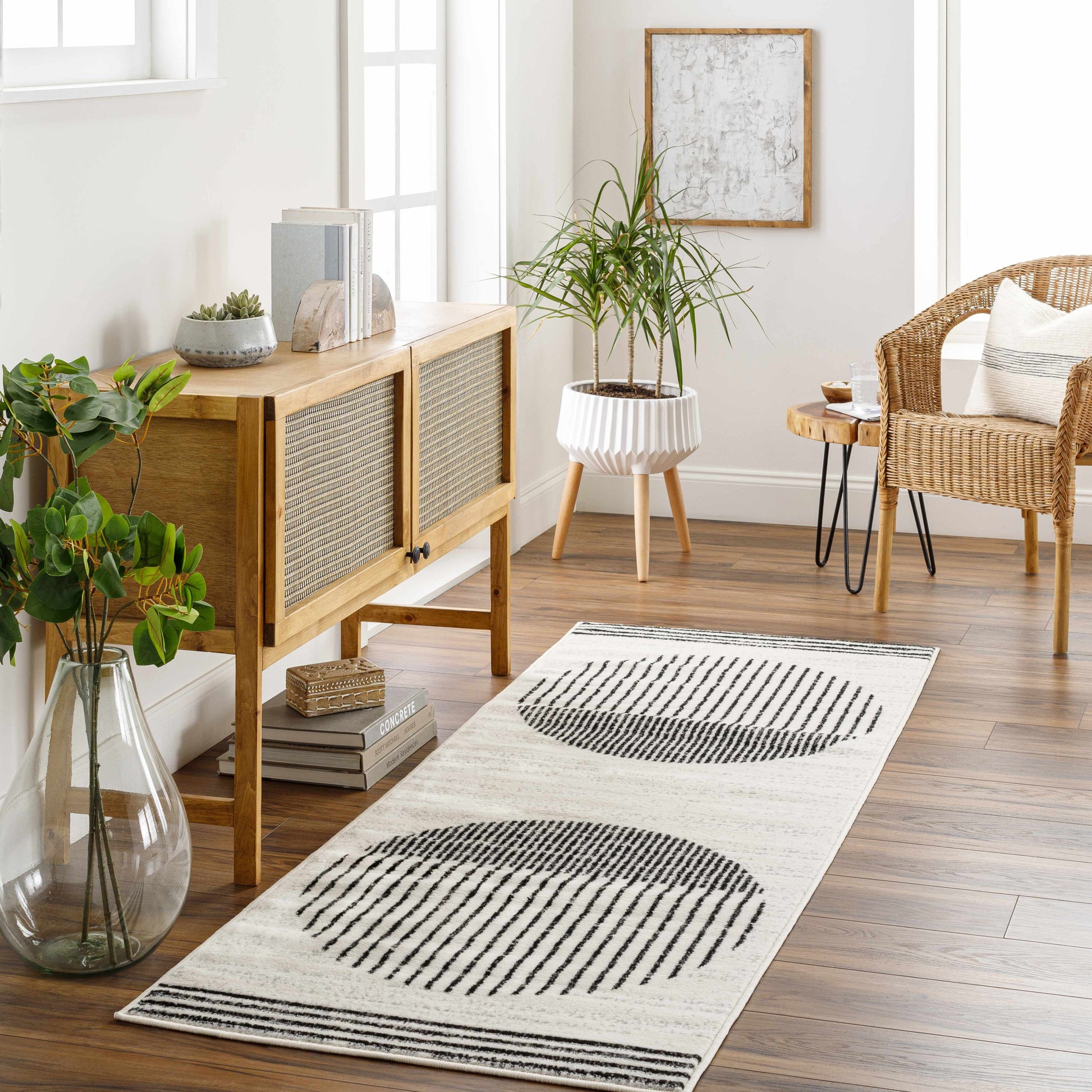 Angus Abstract Black and White Area Rug runner in a modern living room with wood furniture, plants, and natural light.