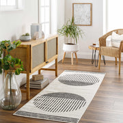 Angus Abstract Black and White Area Rug runner in a modern living room with wood furniture, plants, and natural light.