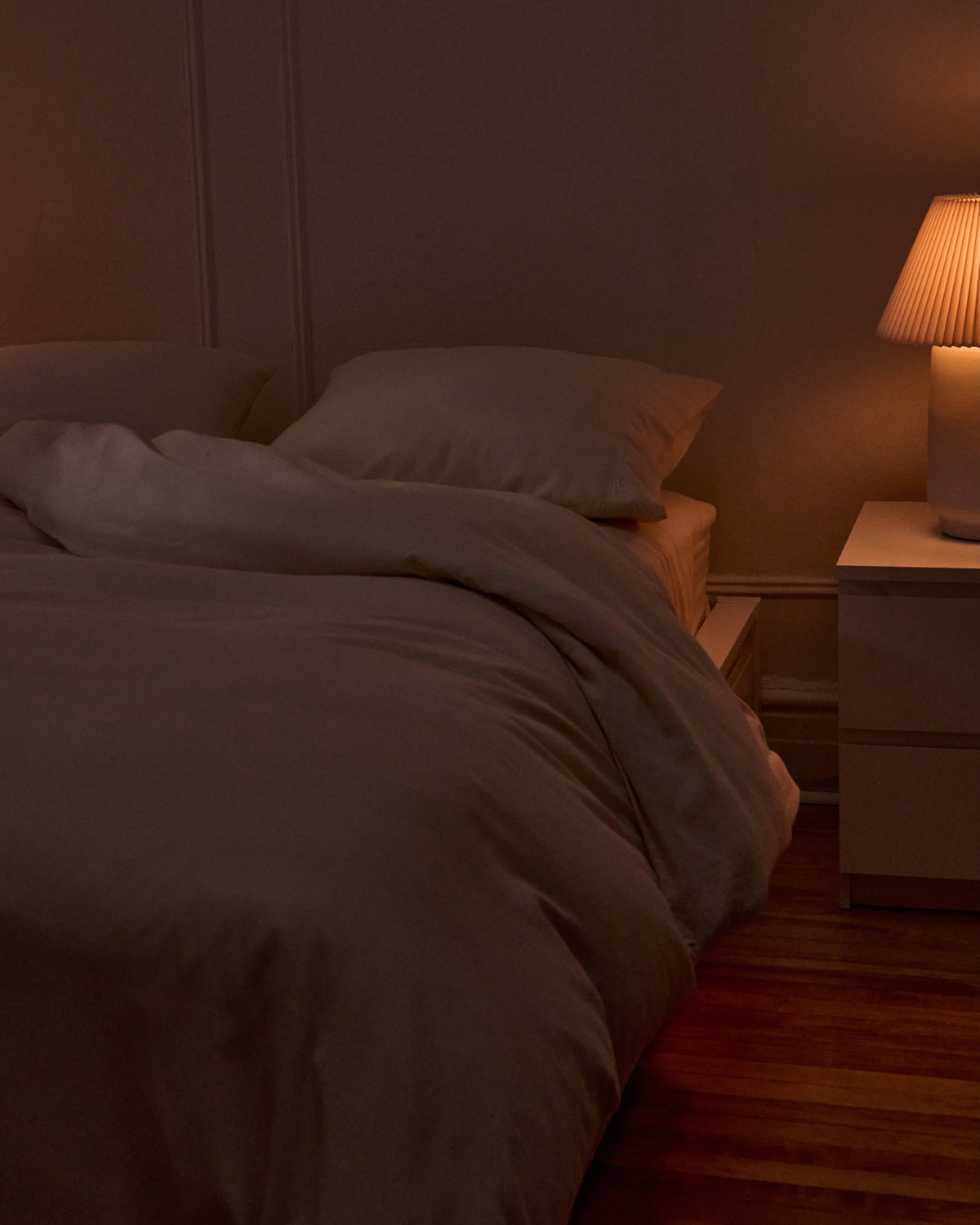 Signature Milk Fibre Deluxe Set Cream duvet cover and pillowcases on a bed in a warm evening bedroom setting