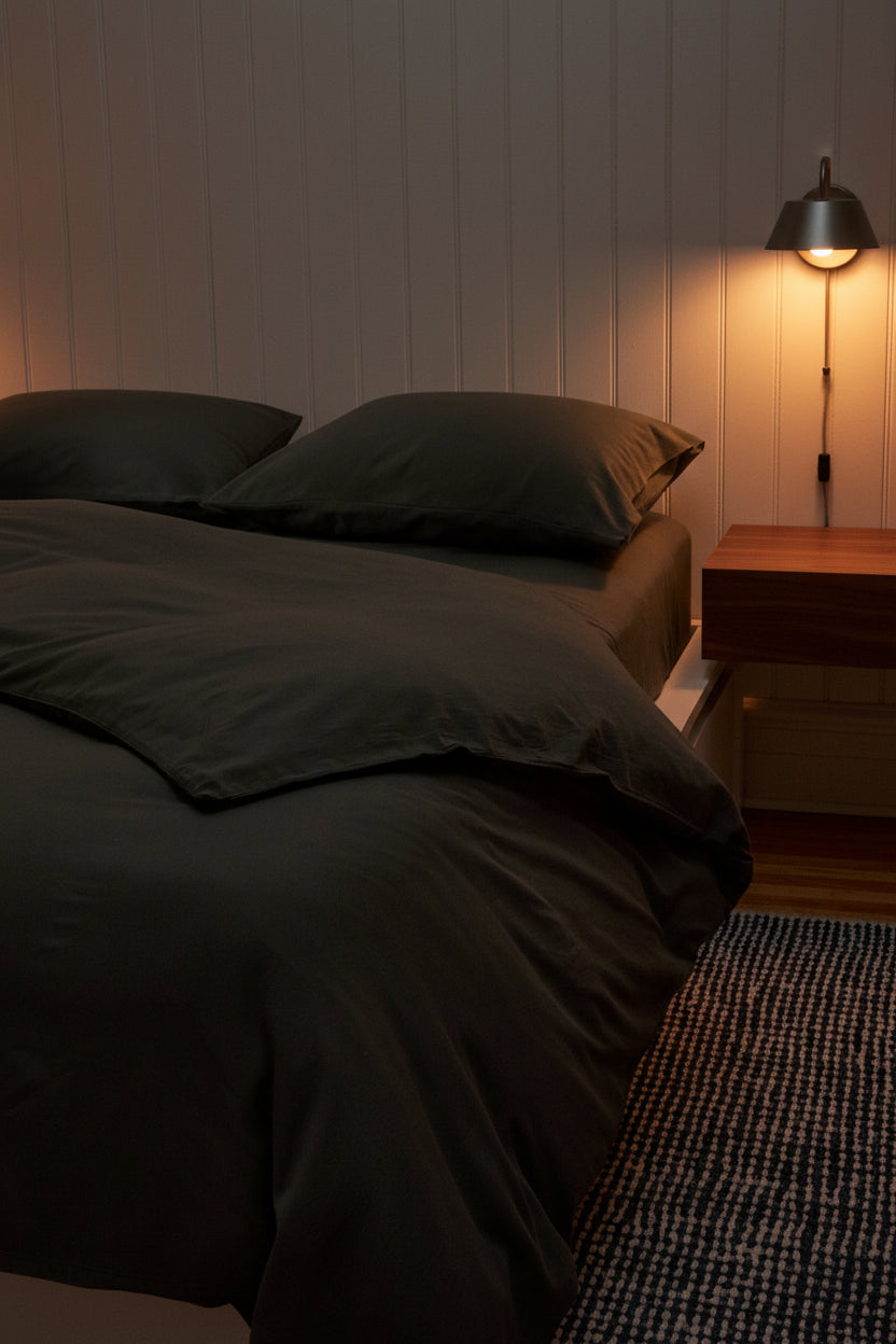 Signature Milk Fibre Deluxe Set Highlands Green duvet cover and pillowcases on a bed in a warm ambient bedroom with pendant wall lamp and wood nightstand