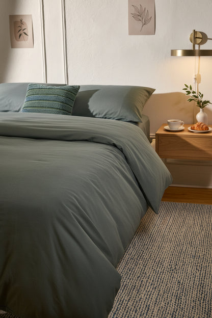 Signature Milk Fibre Duvet Cover Highlands Green on a styled bed with warm neutral bedroom setting and botanical wall art