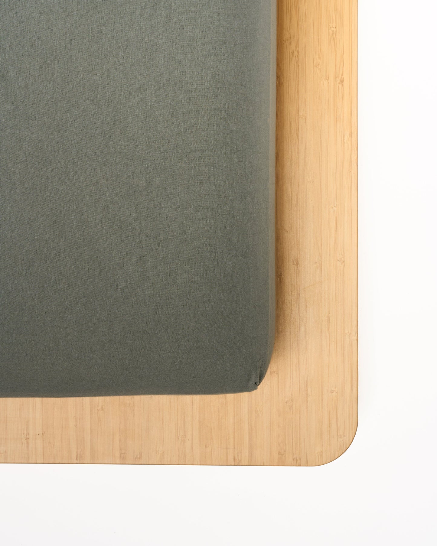 Signature Milk Fibre Sheet Set in Highlands Green fitted sheet corner on natural wood bed frame
