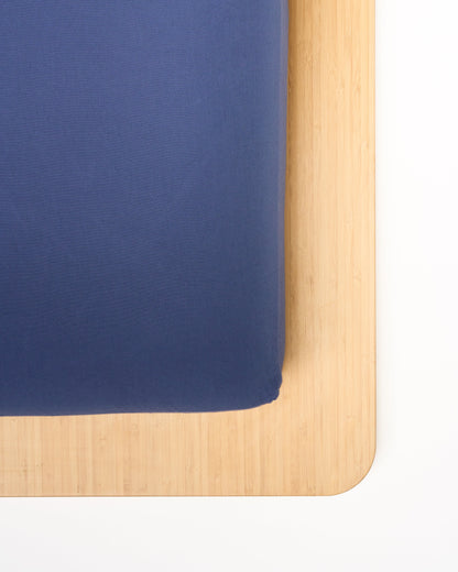 Signature Milk Fibre Sheet Set in Lunar Blue fitted sheet corner on natural wood bed frame