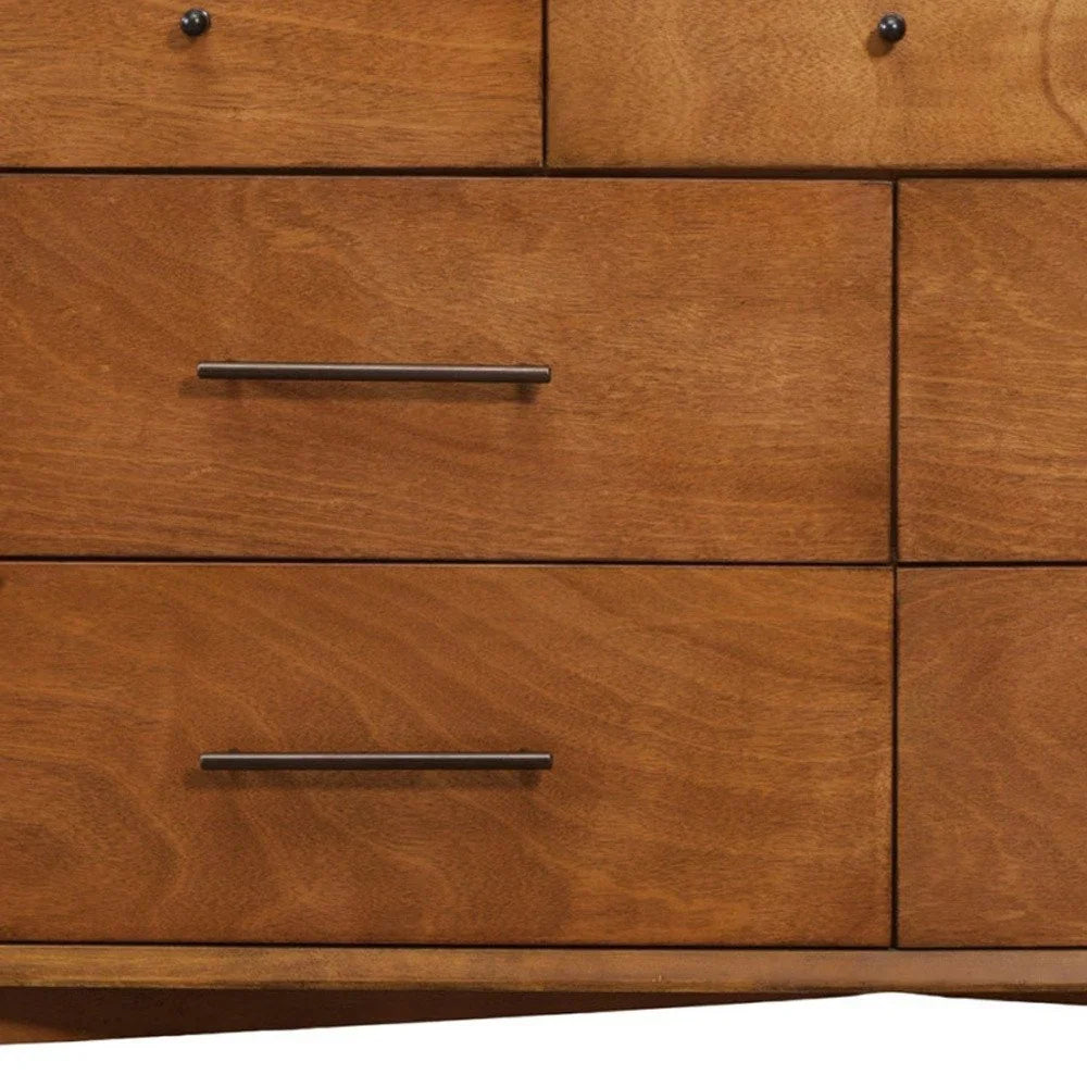 Close-up of mahogany dresser drawer faces showing golden amber grain swirling figure dark bronze bar pulls and curved base apron