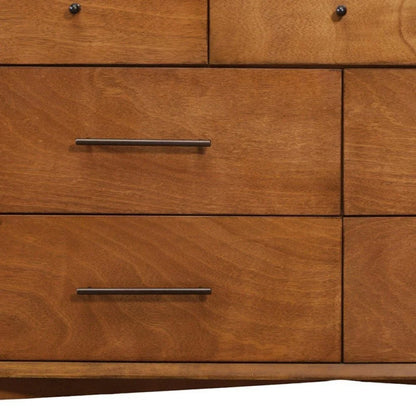 Close-up of mahogany dresser drawer faces showing golden amber grain swirling figure dark bronze bar pulls and curved base apron