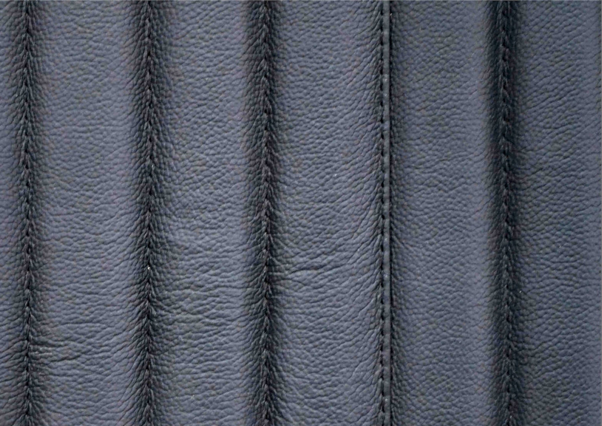 Macro close-up of genuine top grain black leather surface showing natural grain texture and vertical stripe quilting stitching detail with🌿