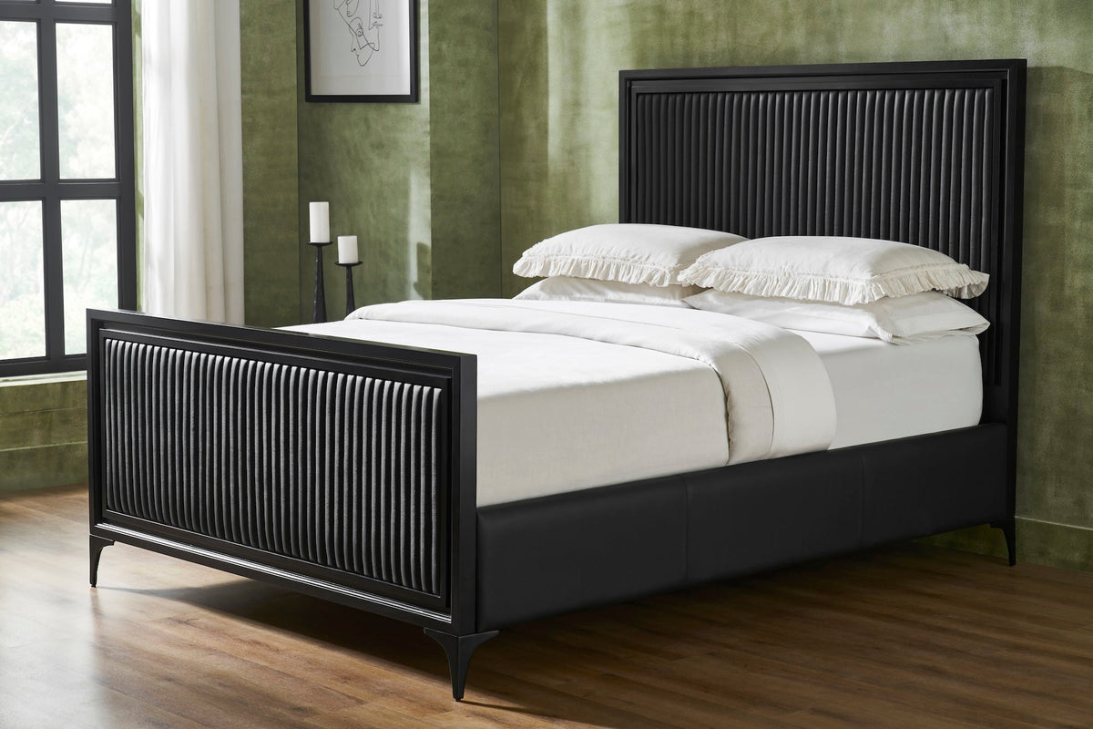 A black genuine leather quilted bed frame styled with white bedding and pillows, vertical stripe quilting on panel headboard and footboard, iron legs, in a modern bedroom with green walls, hardwood floor, and natural window light. 