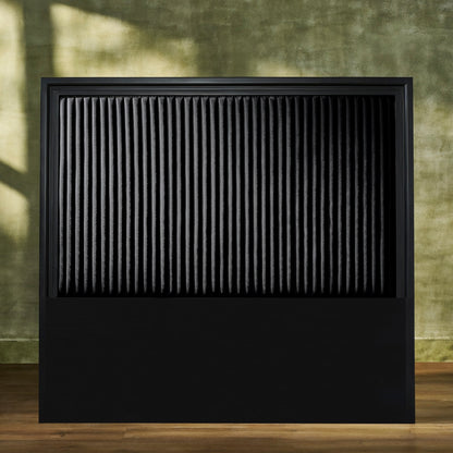 Stanford Genuine Leather Ribbed Headboard in all-black with matte frame and vertical ribbed leather panel styled against an earthy green wall