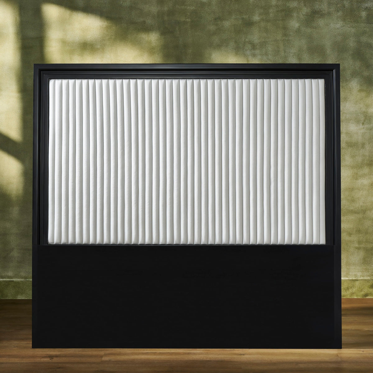 Stanford Genuine Leather Ribbed Headboard with black matte frame and white vertical ribbed leather panel styled against an earthy green wall
