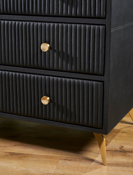 Close-up of vertical ribbed genuine leather drawer fronts with solid brass knobs and angled brass legs on the Stanford black leather chest