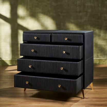 Stanford Ribbed Five-Drawer Leather Chest in black genuine leather with multiple drawers ajar showing depth of micro-suede lined interiors and brass knobs on angled brass legs against sage green wall