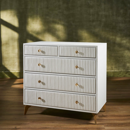 Stanford Ribbed Five-Drawer Leather Chest in white genuine leather at three-quarter angle showing ribbed drawer fronts, brass knobs, and angled brass legs