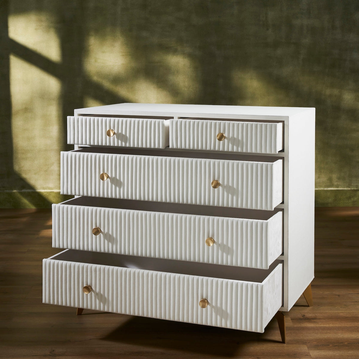 Stanford Ribbed Five-Drawer Leather Chest in white with all drawers open showing micro-suede lined interiors and brass knobs on tapered legs