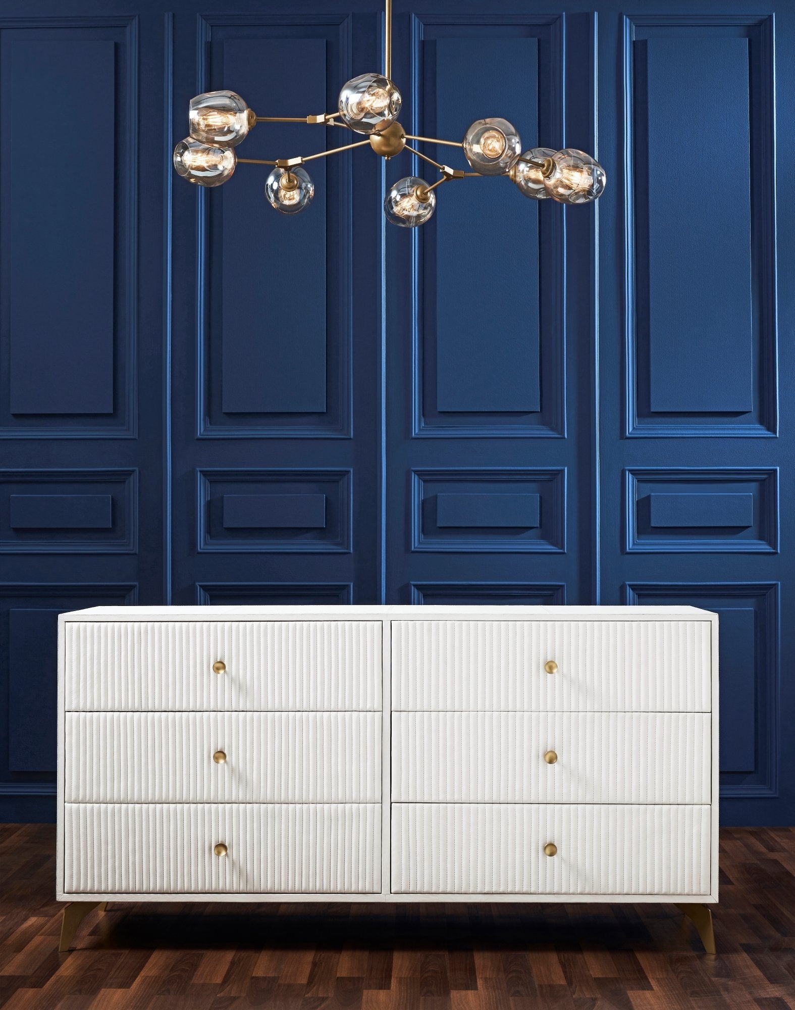 Stanford Ribbed Six-Drawer Leather Dresser white six drawers brass knobs brass-finished legs navy blue paneled wall brass globe chandelier hardwood floor