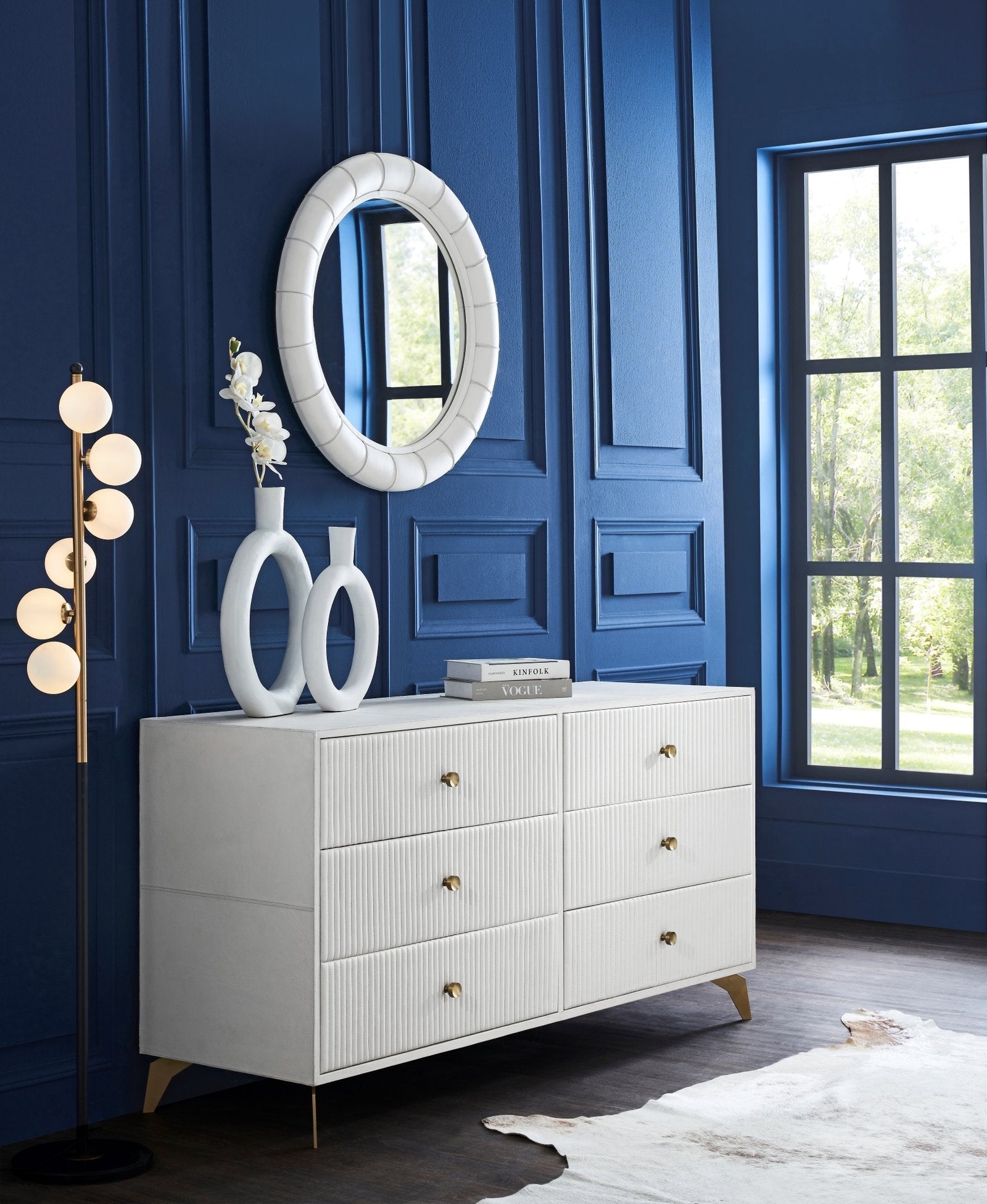 Stanford Ribbed Six-Drawer Leather Dresser white six drawers brass knobs brass-finished legs styled bedroom navy blue paneled wall oval mirror ceramic vases cowhide rug