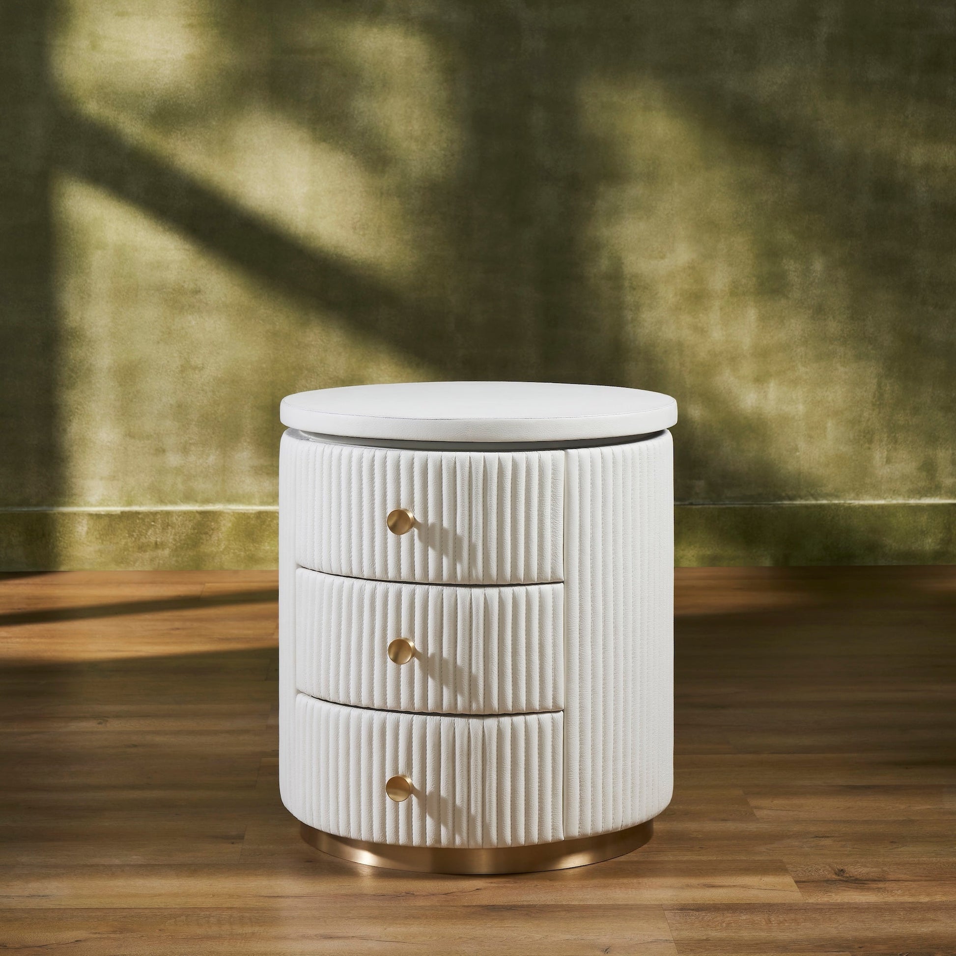 Stanford Round Fluted Leather Nightstand white three drawers brass knobs brass rim base front view warm green background hardwood floor