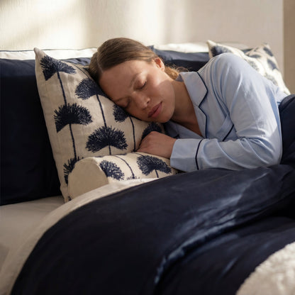 Woman sleeping on Sunday Citizen Palm Leaf Embroidered Bolster Pillow Navy Off White bedding lifestyle 
