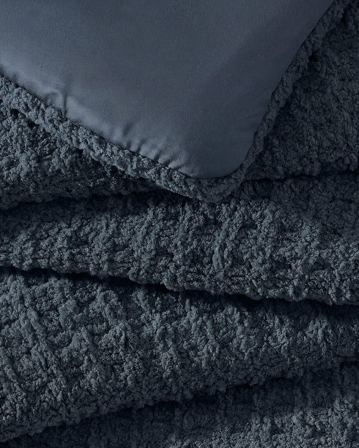 Close-up of Snug Waffle Comforter in Midnight showing plush sherpa interior lining and waffle texture exterior detail