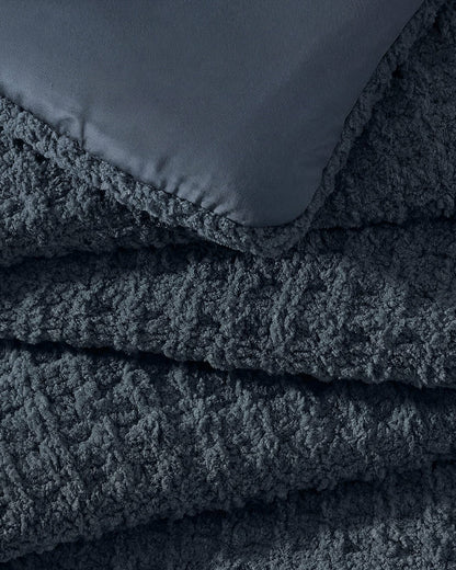 Close-up of Snug Waffle Comforter in Midnight showing plush sherpa interior lining and waffle texture exterior detail