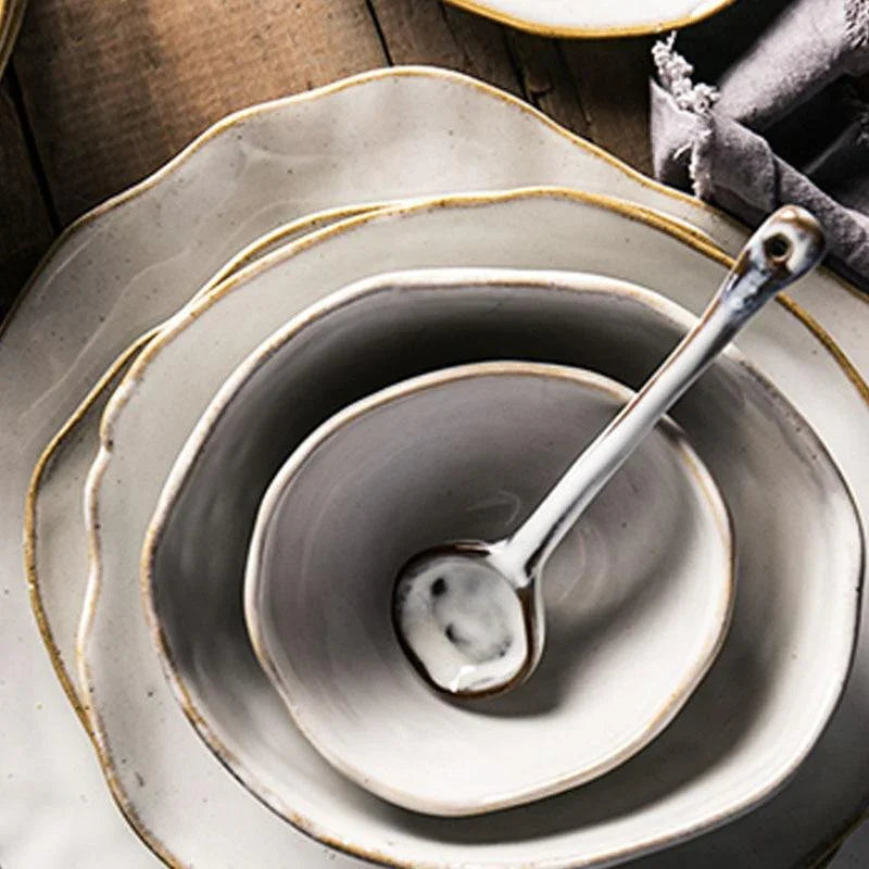 Detailed view of the Thetis Tableware Ceramic Set featuring vibrant glaze dinnerware and a coordinating small spoon with organic edges and handcrafted stoneware texture.