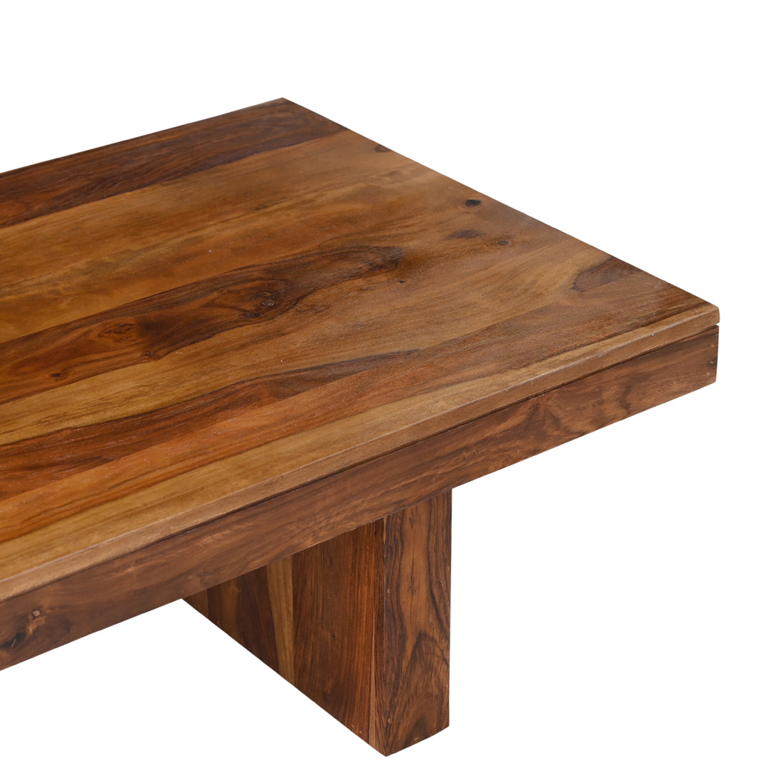 Close-up of solid seesham wood coffee table surface showing natural grain variation, warm brown tones, and chunky block leg construction with hand finished wax finish