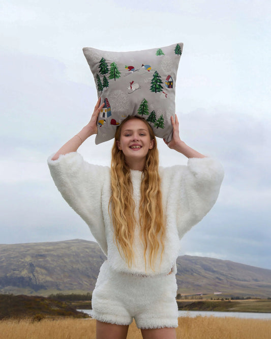 Woman outdoors holding velvet embroidered throw pillow with forest and animal design, Fluent Trends
