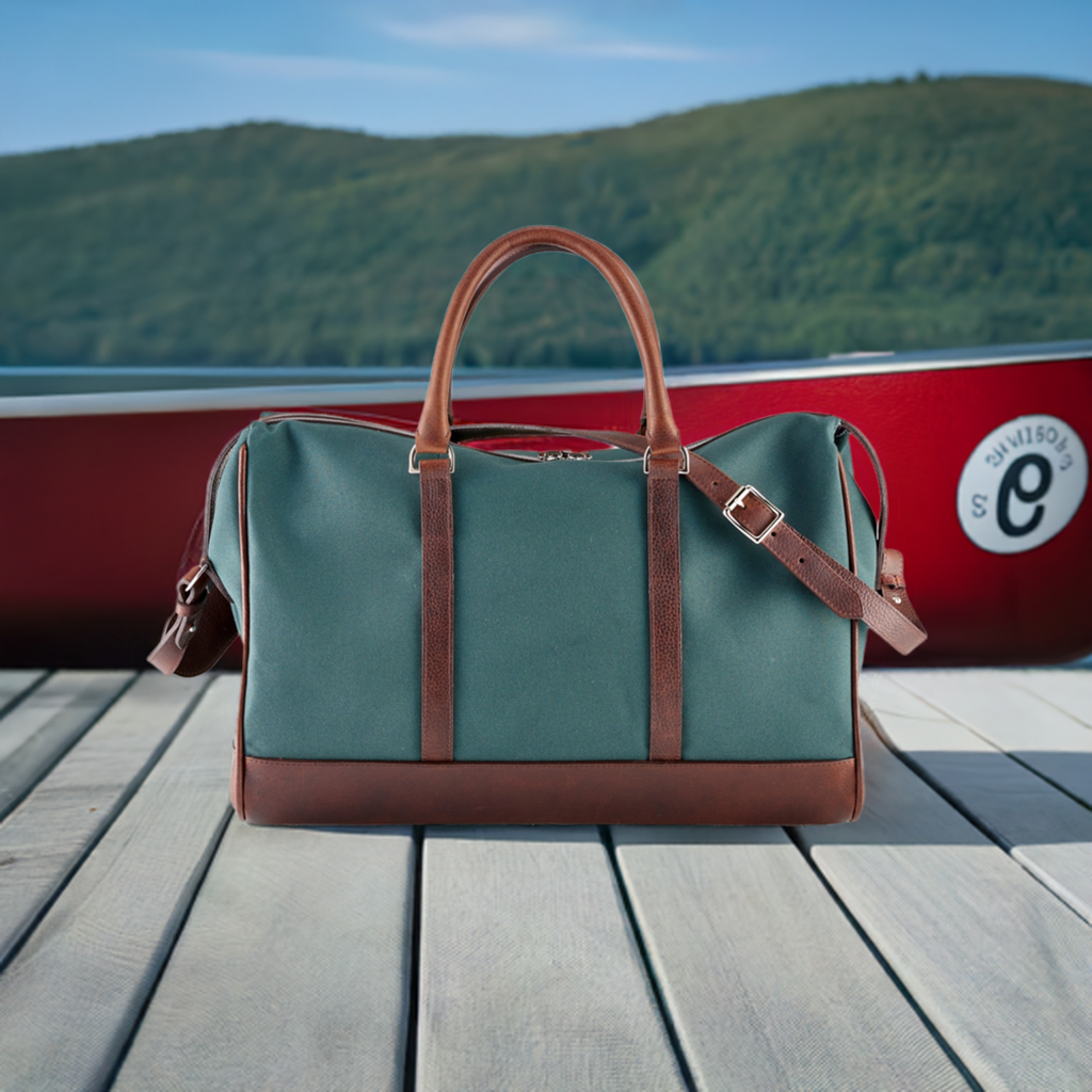 Wanderlust Weekender canvas duffel Classic Green on wooden dock beside red boat with brown leather trim handles and shoulder strap against lake backdrop

