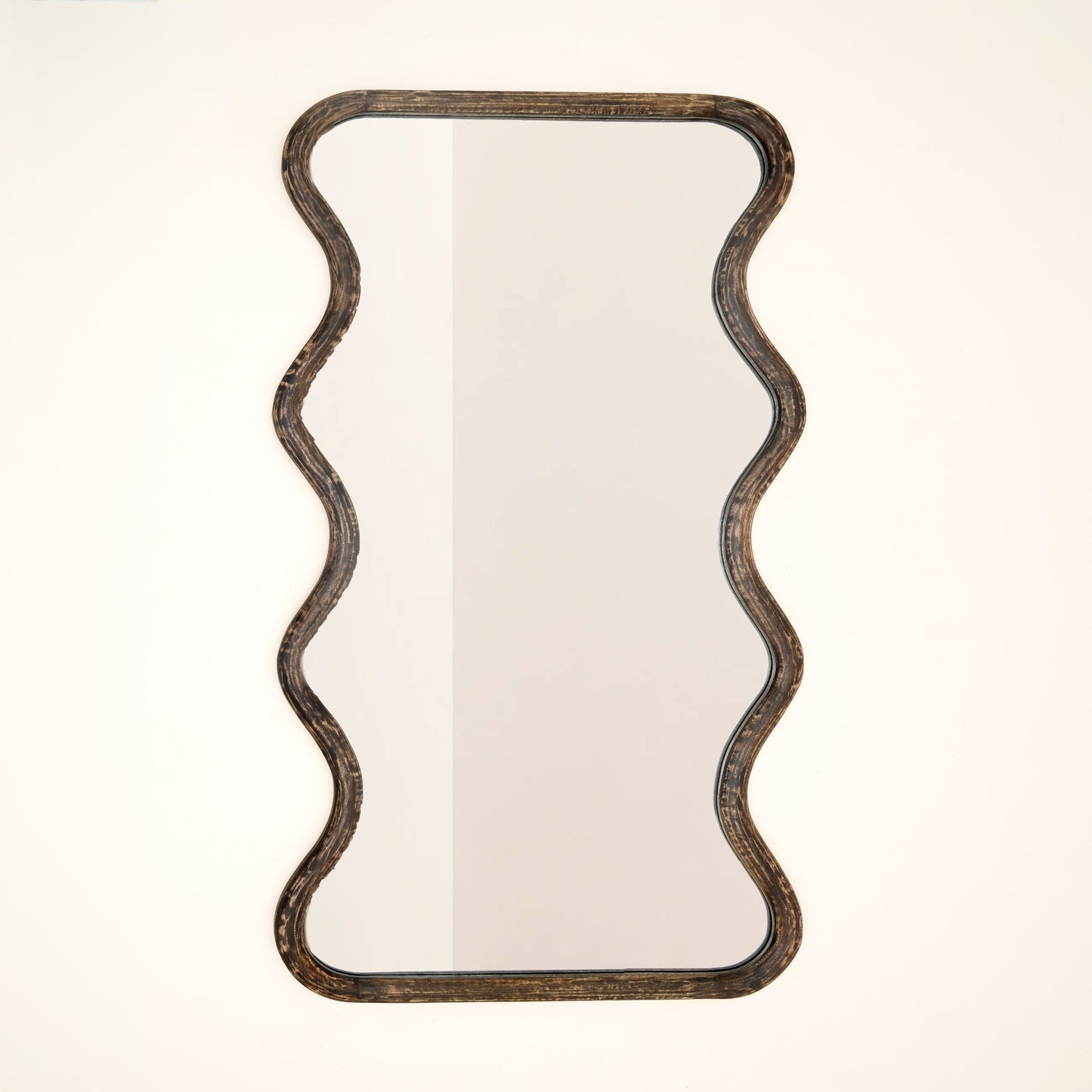 Wavy mango wood wall mirror with sculptural wave silhouette and brown antique finish against a neutral white background

