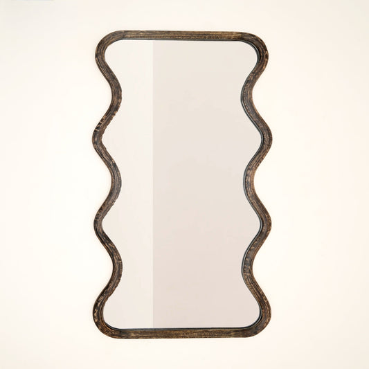 Wavy mango wood wall mirror with sculptural wave silhouette and brown antique finish against a neutral white background

