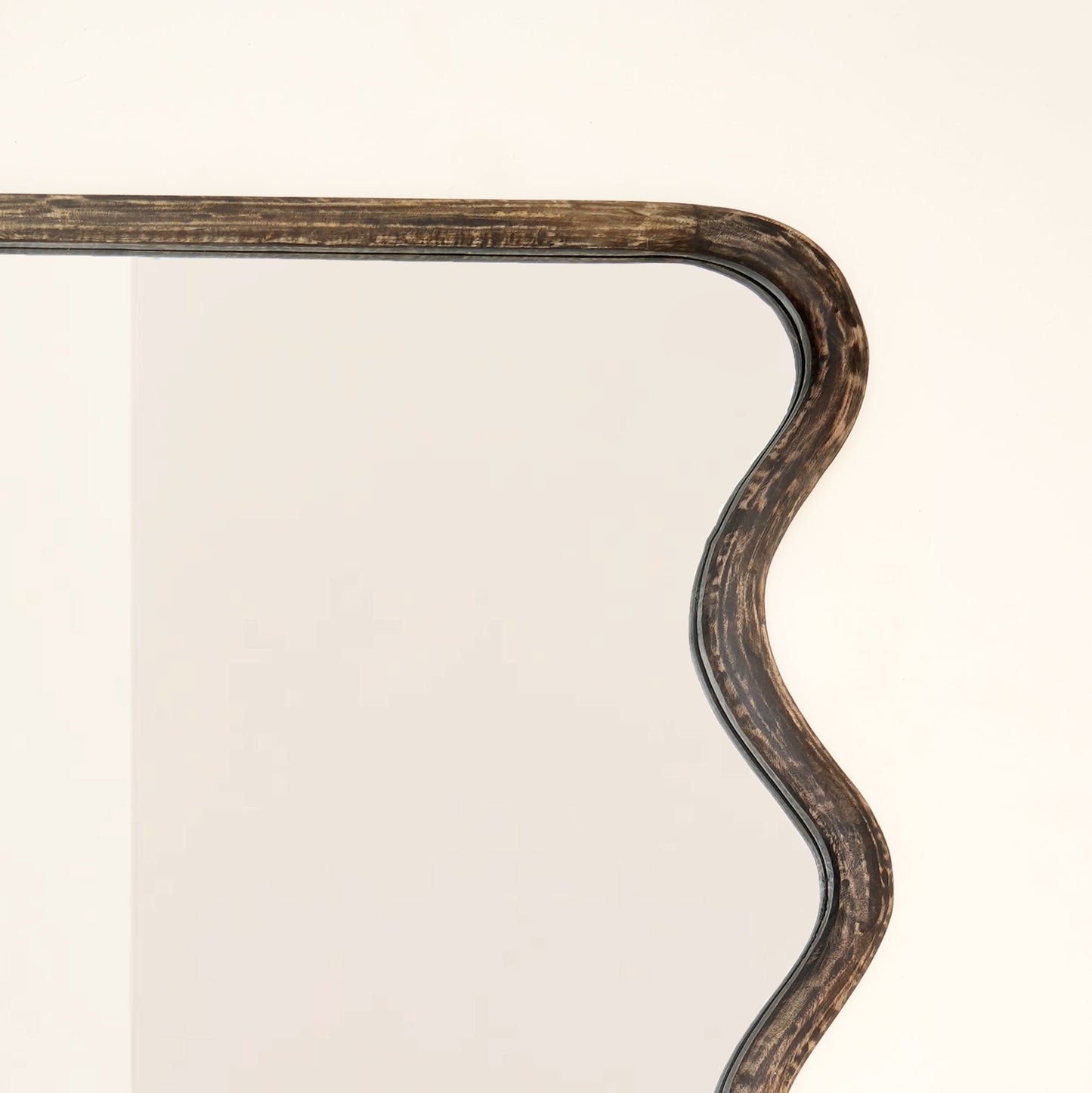 Top corner close-up of wavy mango wood wall mirror showing handcrafted wave curve detail and brown antique finish wood grain texture

