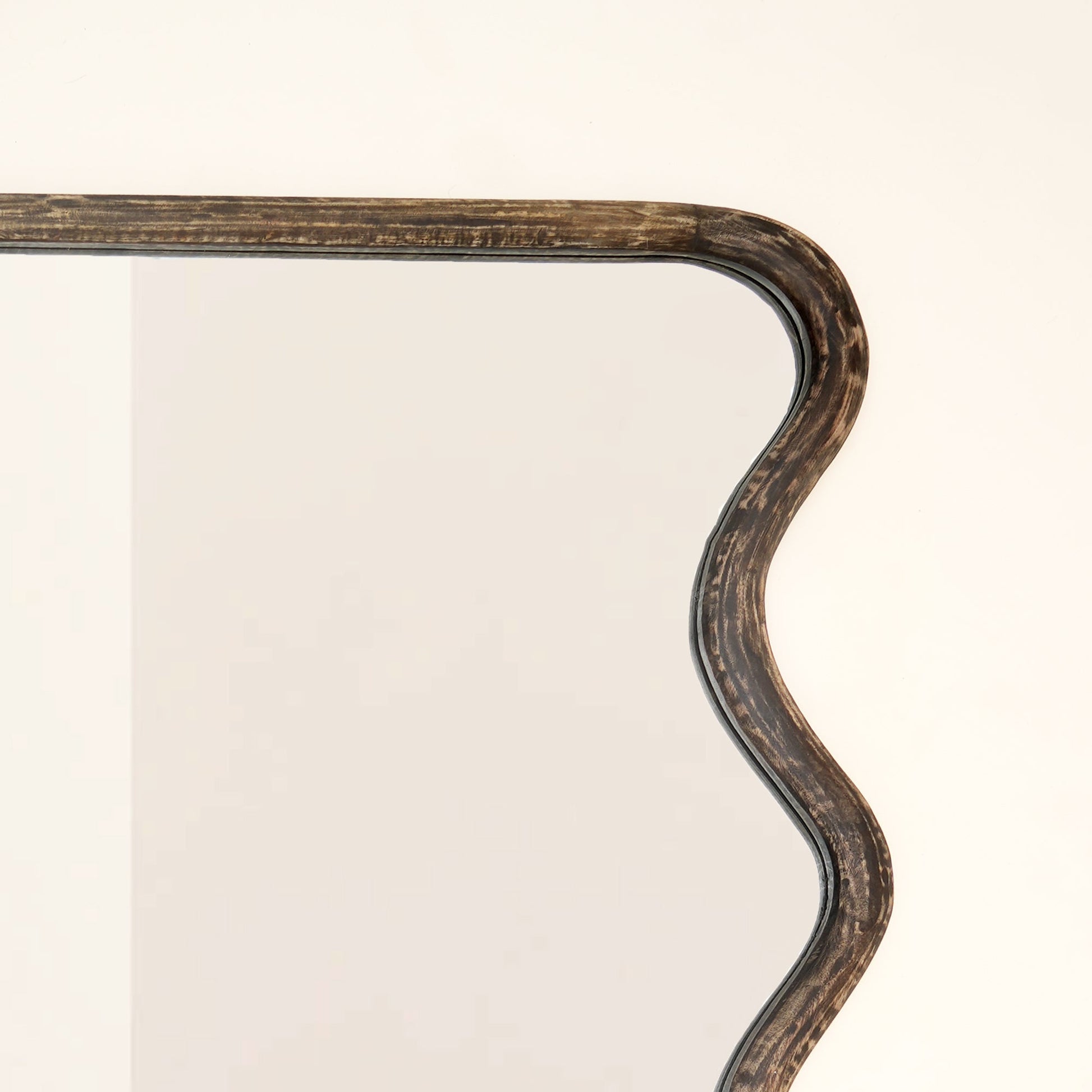 Top corner close-up of wavy mango wood wall mirror showing handcrafted wave curve detail and brown antique finish wood grain texture

