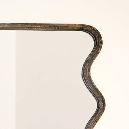 Top corner close-up of wavy mango wood wall mirror showing handcrafted wave curve detail and brown antique finish wood grain texture

